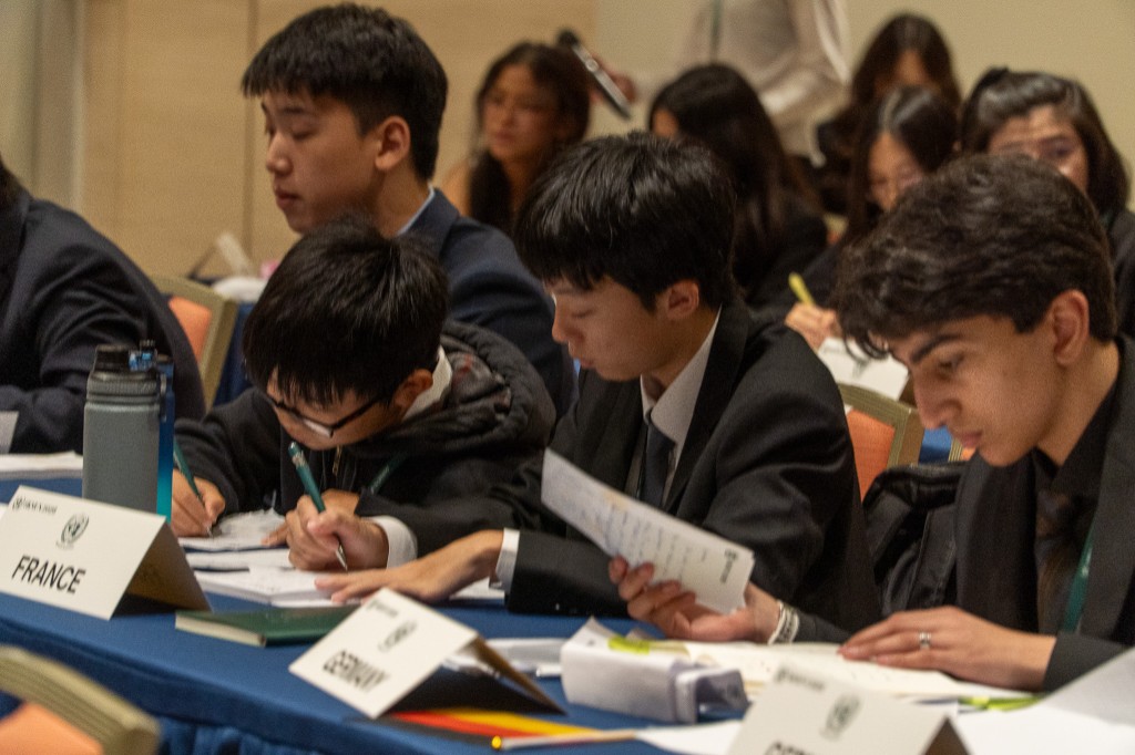 Delegates writing notes at France–Germany tables